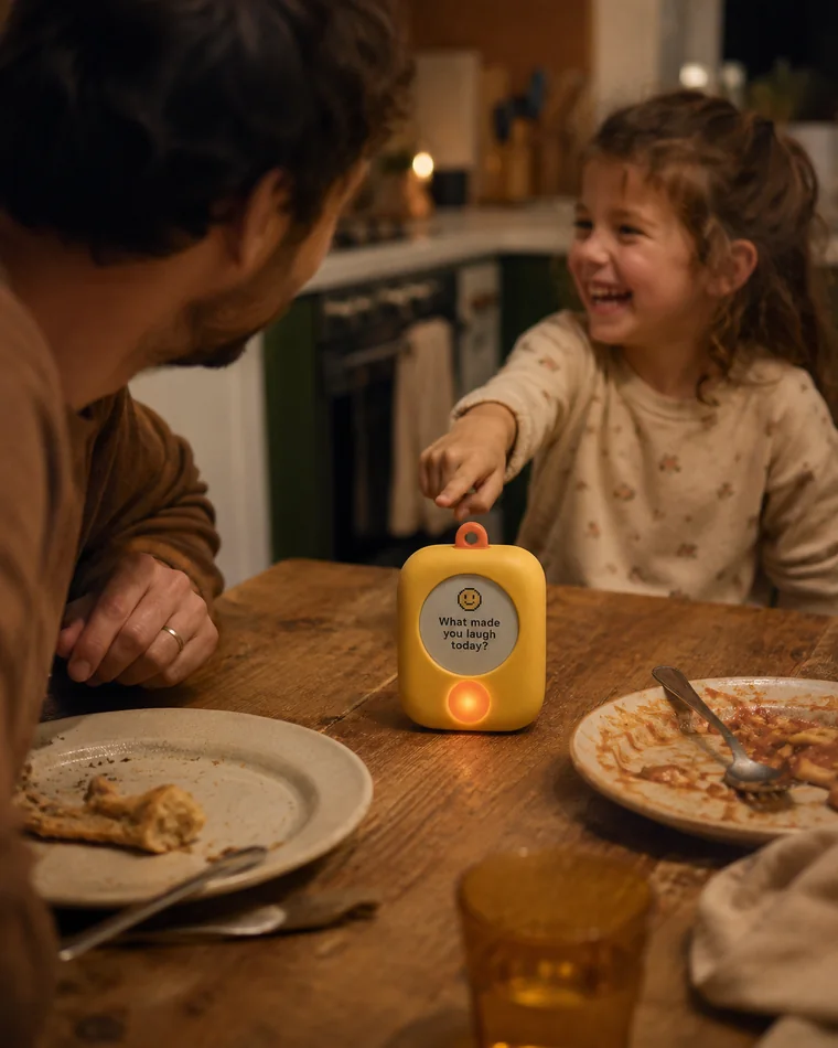 A dad and his laughing daughter having a dinner-table conversation started by the Warm device